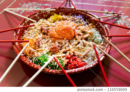 Serving of yusheng or yee sang with raw salmon belly during Chinese New Year with chop sticks laid around plate for good luck and prosperity Serving of yusheng or yee sang with raw salmon belly during Chinese New Year with chop sticks laid around plate for good luck and prosperity 110559009