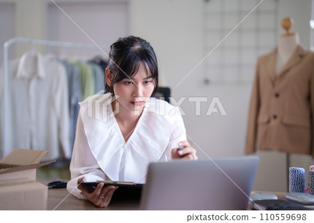 Young asian merchant women checking purchase online order and client information on laptop to taking notes in clipboard while working and shipping delivery for online shopping business in home office Young asian merchant women checking purchase online order and client information on laptop to taking notes in clipboard while working and shipping delivery for online shopping business in home office 110559698