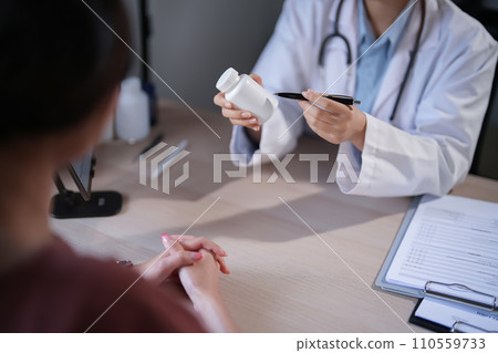 Asian psychologist women showing pills bottle to explaining medicine and prescription to female patient while giving counseling to explaining about mental health therapy to female patient in clinic 110559733