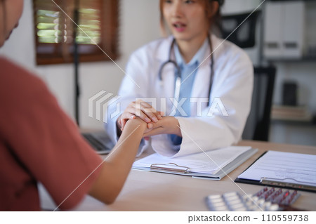 Asian psychologist women holding hand to encouraging patient and giving counseling about mental health therapy in clinic while female patient stress and anxiety with psychological health problem 110559738