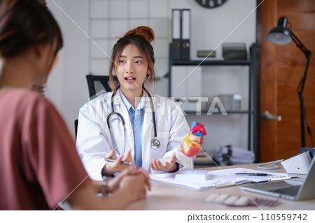 Asian cardiologist doctor women explaining about anatomical of human heart model and giving counseling about medical and mental health therapy to female patient after examining health in hospital 110559742