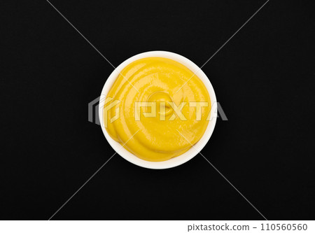 White bowl of yellow American mustard on table 110560560