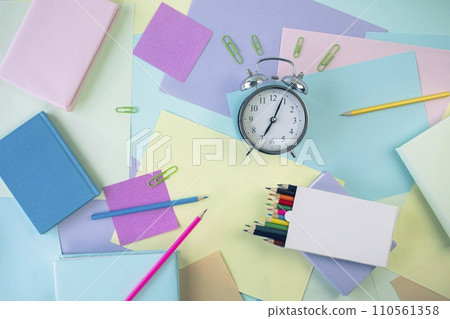 Back to school, stationery, alarm clock, stack of books, paper and colored pencils on student's desk, top view 110561358