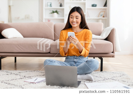 Pretty young asian lady entrepreneur using smartphone, home interior Pretty young asian lady entrepreneur using smartphone, home interior 110561591