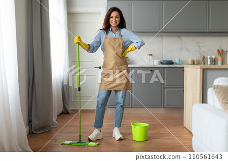 Smiling young woman with mop and bucket enjoys house cleaning Smiling young woman with mop and bucket enjoys house cleaning 110561643