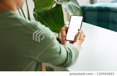 Over shoulder view black guy using phone with blank screen 110561693