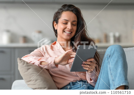 Relaxed woman browsing on tablet in cozy home setting 110561710