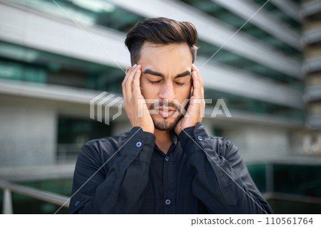 Portrait of stressed middle eastern businessman suffering from headache outside Portrait of stressed middle eastern businessman suffering from headache outside 110561764