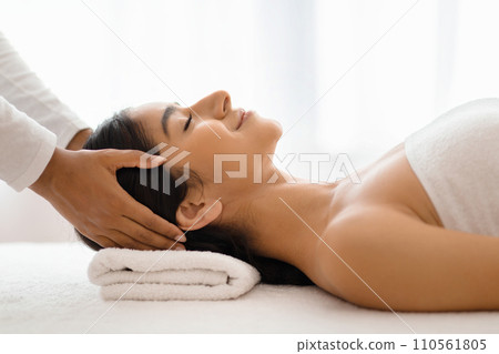 Masseuse making relaxing head massage for young beautiful indian lady Masseuse making relaxing head massage for young beautiful indian lady 110561805