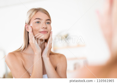 Smiling lady gently holds her face touching smooth skin indoor Smiling lady gently holds her face touching smooth skin indoor 110561965