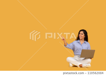 Cheerful young woman in a blue blouse and white pants sitting cross-legged on the floor Cheerful young woman in a blue blouse and white pants sitting cross-legged on the floor 110562084