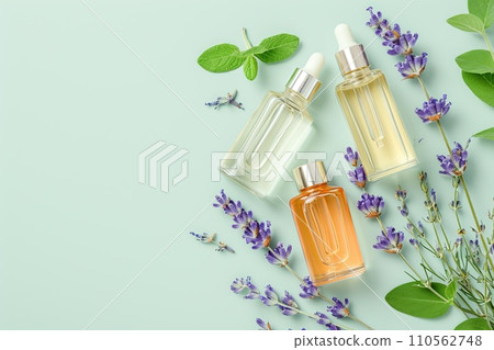 Elegant flat lay of body oils and perfume bottles with lavender sprigs on a pastel background, minimalist style 110562748