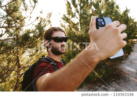 Hiker man in sunglasses using his mobile phone in the mountain woods Hiker man in sunglasses using his mobile phone in the mountain woods 110563186