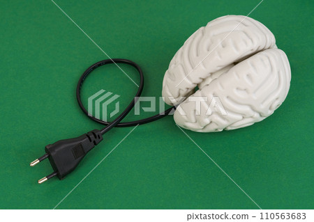 Brain with an electric wire for charging on a green background. 110563683