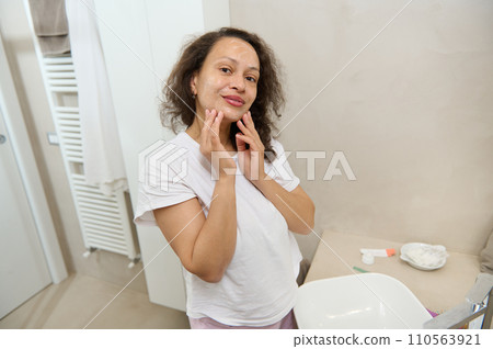 Attractive middle aged woman smiling looking at camera while applying moisturizing cleansing foam on her face Attractive middle aged woman smiling looking at camera while applying moisturizing cleansing foam on her face 110563921