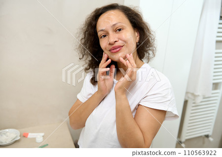 Young woman touching face, taking care of her flawless skin, applying cleansing foam, smiling cutely looking at camera Young woman touching face, taking care of her flawless skin, applying cleansing foam, smiling cutely looking at camera 110563922