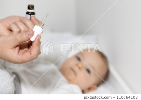 Mom giving vitamin D3 to newborn baby for care of the proper functioning of muscles and bone formation, healthcare concept Mom giving vitamin D3 to newborn baby for care of the proper functioning of muscles and bone formation, healthcare concept 110564108