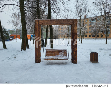 Wooden swing outside in winter under a thick layer of snow. The theme of winter cold and entertainment. 110565031