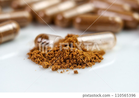 Nutrient supplement powder and broken brown herbal medicine capsule. Alternative medicine drug 110565396