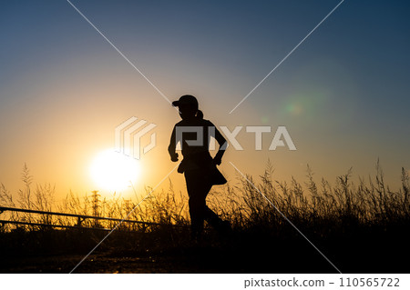 sunset and silhouette of jogger 110565722