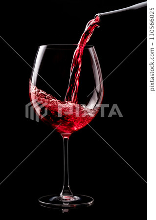 Red wine pouring into glass isolated on black background. Rose wine splashing in glassware. Red wine pouring into glass isolated on black background. Rose wine splashing in glassware. 110566025