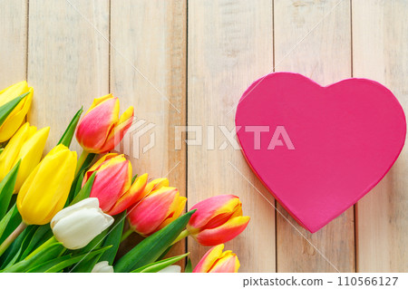 Tulips and heart on a wooden background. Valentine's day greeting card concept. Tulips and heart on a wooden background. Valentine's day greeting card concept. 110566127