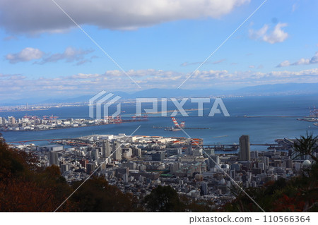 A view of Osaka Bay with clouds, blue sky, and blue sea, the city of Kobe, and the cityscape and mountains of Osaka on the opposite shore. A view of Osaka Bay with clouds, blue sky, and blue sea, the city of Kobe, and the cityscape and mountains of Osaka on the opposite shore. 110566364