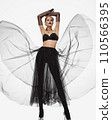 Beautiful woman in a transparent black skirt, bodice and neck decoration posing on a white background 110566395