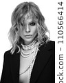 A beautiful woman with loose hair, in a jacket and beads, poses in the studio 110566414