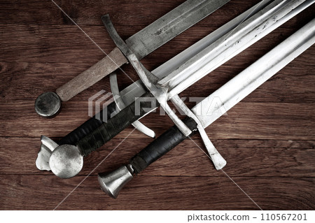 Medieval swords on wooden backgrond. 110567201