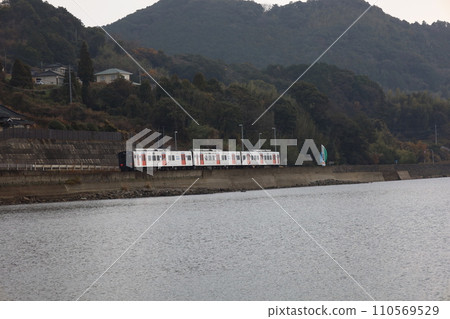 YC1 diesel train heading towards Sonogi Station through calm Omura Bay YC1 diesel train heading towards Sonogi Station through calm Omura Bay 110569529