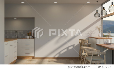 Interior design of a modern white, spacious kitchen with a dining table near the glass window. 110569798