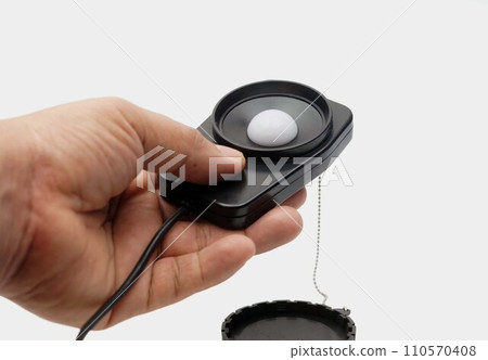 Close up a hand catch a light probe of a LUX meter. 110570408
