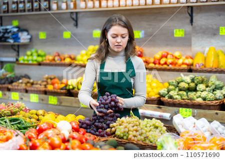 Young woman seller lays grapes on counter 110571690