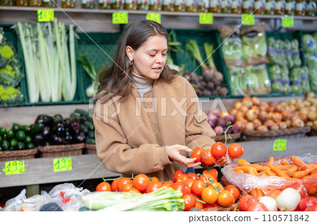 Young woman choosing tomatoes in vegetable shop Young woman choosing tomatoes in vegetable shop 110571842