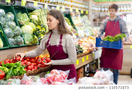 Young woman seller lays out tomatoes on counter Young woman seller lays out tomatoes on counter 110571873