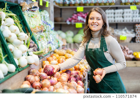 Female seller working in supermarket and lays out onions on counter 110571874