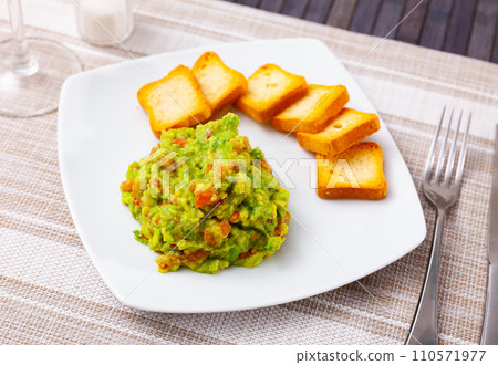 Portion of fresh guacamole with rusks served on table Portion of fresh guacamole with rusks served on table 110571977