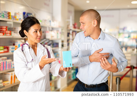 Woman pharmacist advises man medicine for heart pain. Help in choosing a medicine in pharmacy Woman pharmacist advises man medicine for heart pain. Help in choosing a medicine in pharmacy 110571993