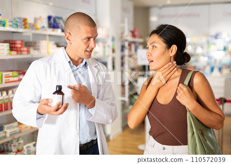 Woman complains to a pharmacist about a sore throat. Help in choosing a medicine in pharmacy Woman complains to a pharmacist about a sore throat. Help in choosing a medicine in pharmacy 110572039