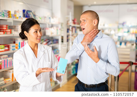 Man complains to a female pharmacist about a sore throat. Help in choosing a medicine in pharmacy Man complains to a female pharmacist about a sore throat. Help in choosing a medicine in pharmacy 110572057