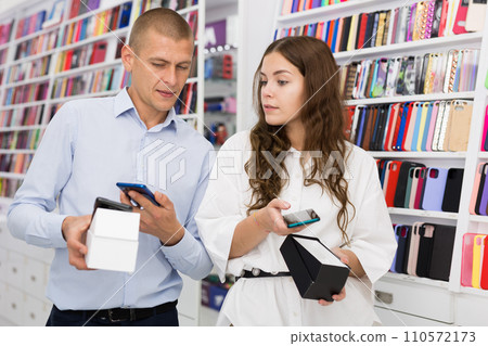 Electronics store employee helping a woman to choose new smartphone 110572173