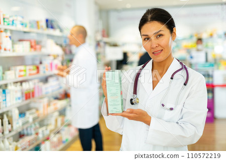 Female pharmacist offers medicine while standing in the trading floor of pharmacy 110572219