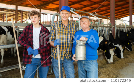 Various aged dairy farm workers in cowshed Various aged dairy farm workers in cowshed 110572249