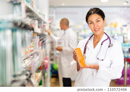 Oriental female pharmacist standing in salesroom of drugstore 110572406