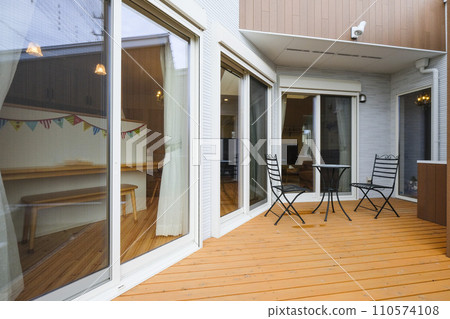 Western-style architecture with a wooden deck, table, and chairs Western-style architecture with a wooden deck, table, and chairs 110574108