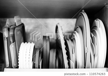 Narrow depth of field picture of an open kitchen cabinet with rows of organized storage of plastic lids. Narrow depth of field picture of an open kitchen cabinet with rows of organized storage of plastic lids. 110574263