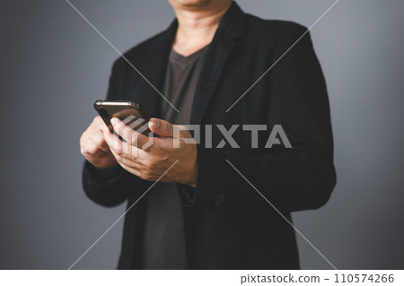 Businessman in suit standing sideways holding and touch smartphone. Businessman in suit standing sideways holding and touch smartphone. 110574266