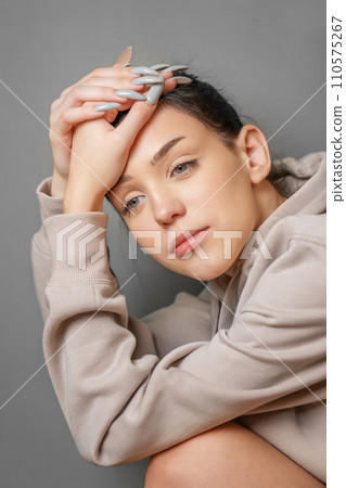 Pensive thoughtful young girl wearing sweatshirt with hood 110575267