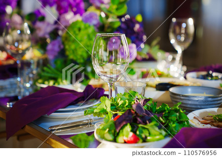 Beautiful festive table setting with flowers and purple napkins. Beautiful festive table setting with flowers and purple napkins. 110576956